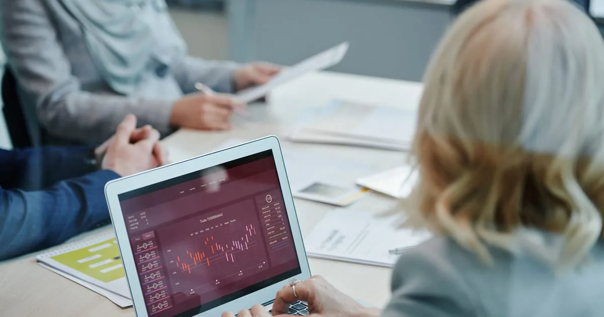 Marketing manager reviewing website search traffic charts on a laptop at an office desk