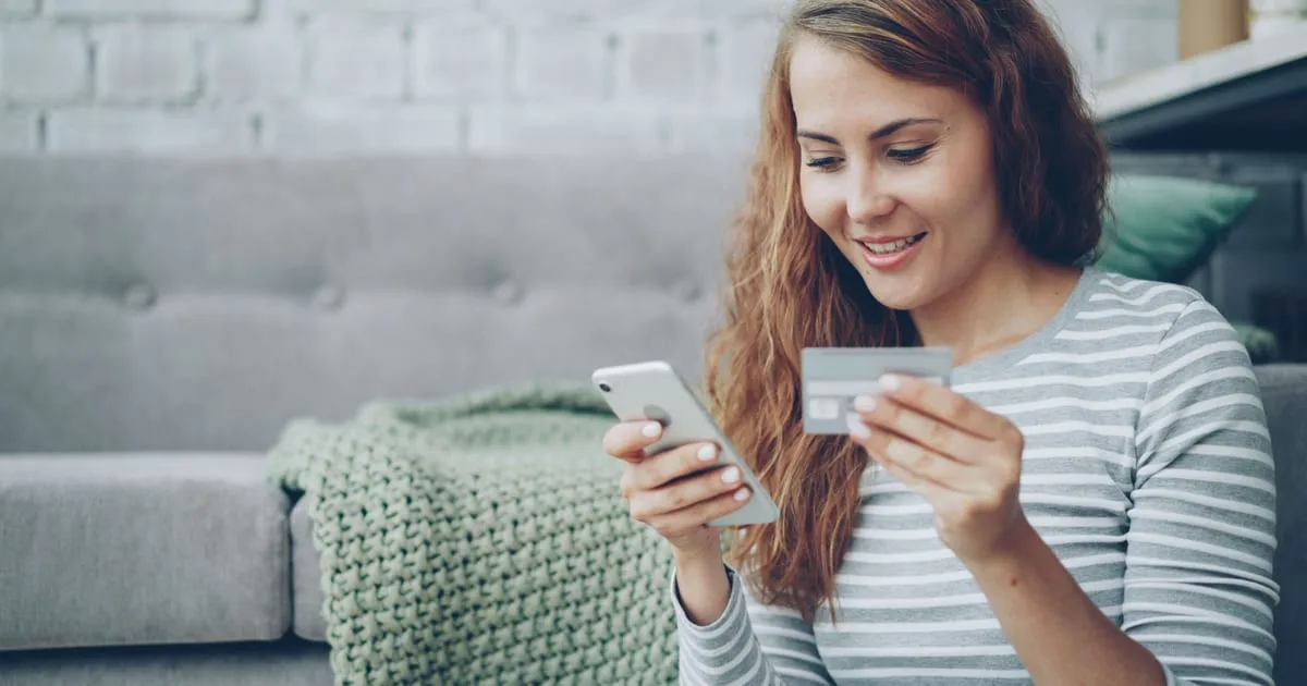 Shopper holding a smartphone and comparing products in an AI chat before buying online