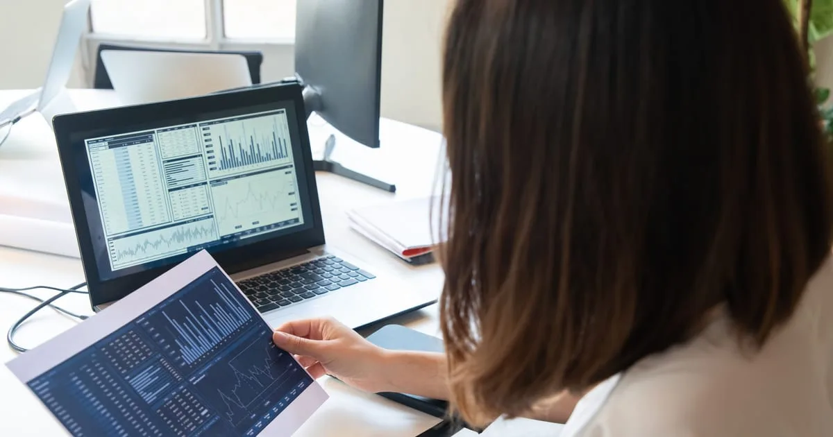 Marketer reviewing search ad campaign results on a laptop at an office desk