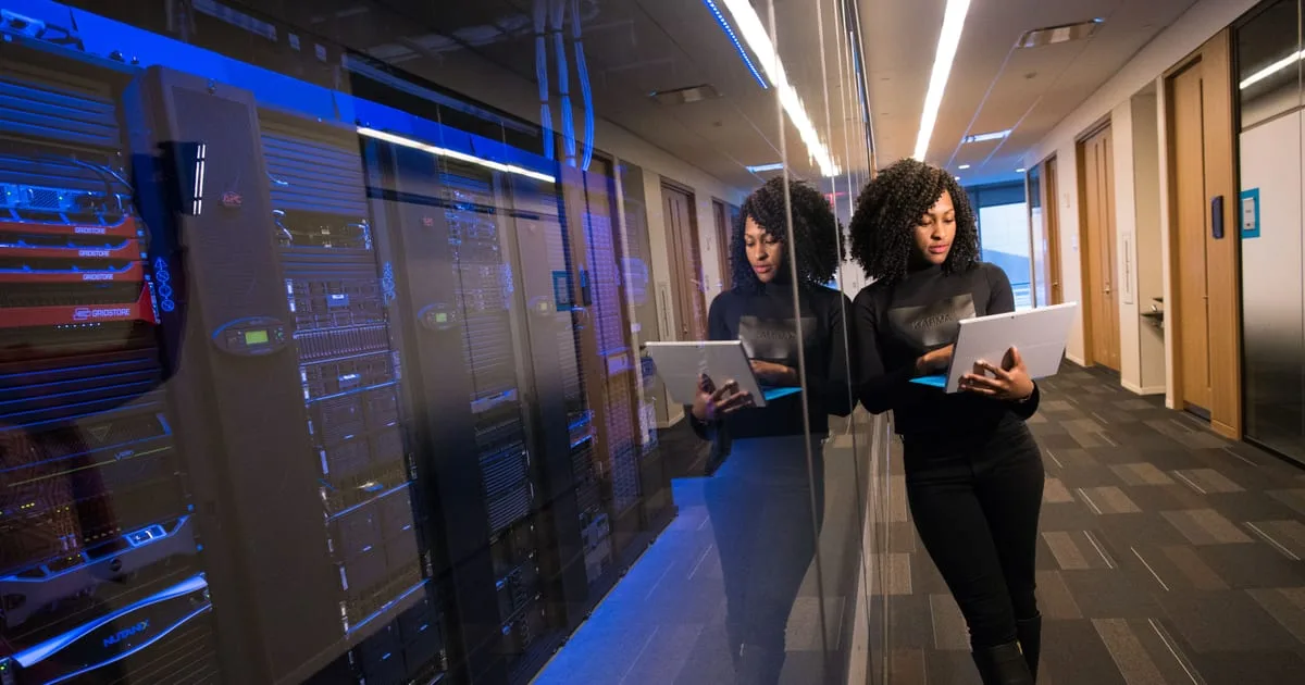 Technician working on a laptop between server racks in a data center