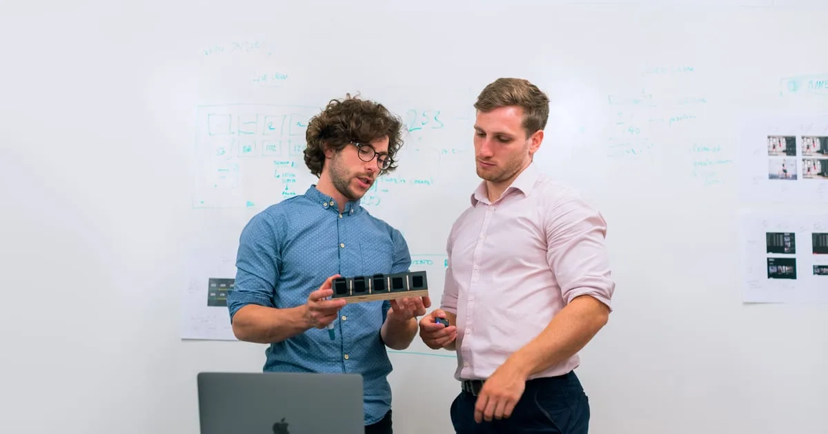 Business owner and developer reviewing an app prototype together on a laptop in a small office