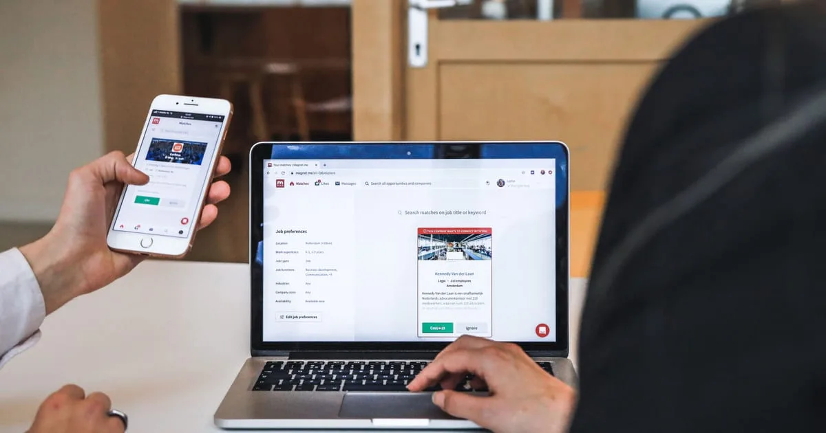 Person testing a business website on a laptop and a smartphone at an office desk